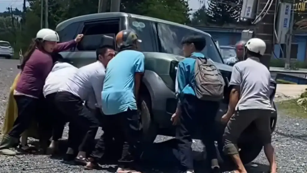 Người lớn, trẻ em hợp sức nâng ô tô điện cứu học sinh kẹt dưới gầm