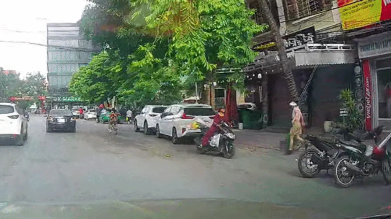 Người phụ nữ lao đầu vào ôtô để nhặt quả xoài rụng